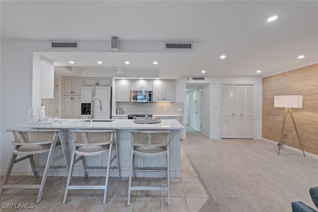 kitchen with a kitchen bar, high end refrigerator, sink, light colored carpet, and kitchen peninsula