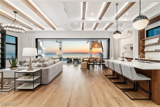 living room with beam ceiling, ceiling fan with notable chandelier, light hardwood / wood-style flooring, and sink