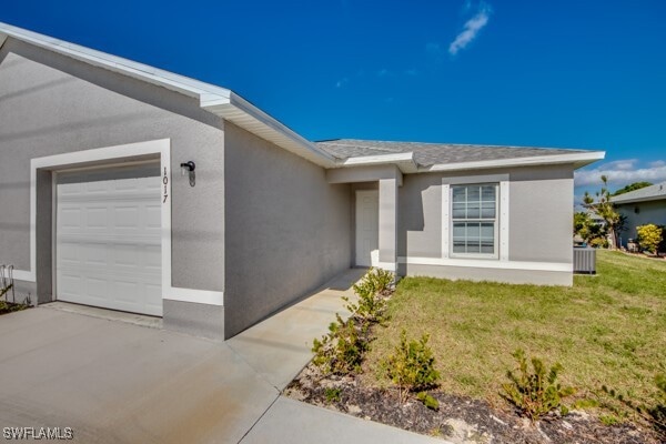 view of front of property with central AC unit, a garage, and a front lawn