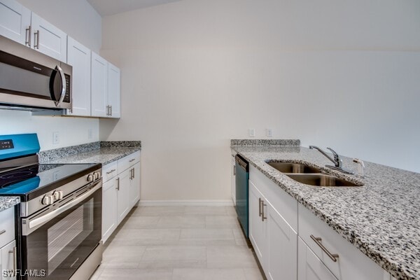 kitchen with light stone counters, sink, white cabinetry, and stainless steel appliances