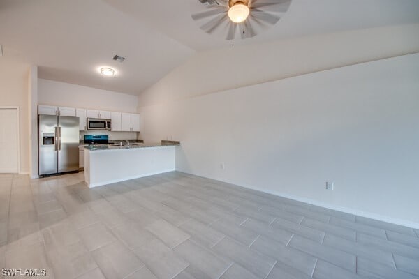 kitchen with kitchen peninsula, appliances with stainless steel finishes, ceiling fan, white cabinets, and lofted ceiling