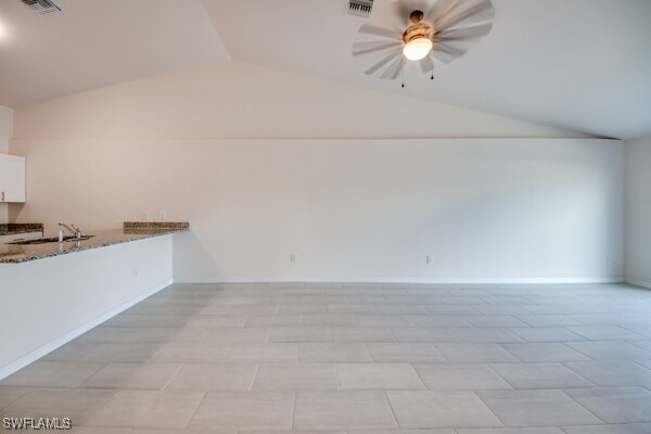 unfurnished living room featuring light tile patterned floors, ceiling fan, lofted ceiling, and sink