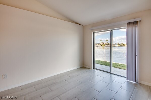 unfurnished room with a water view and lofted ceiling