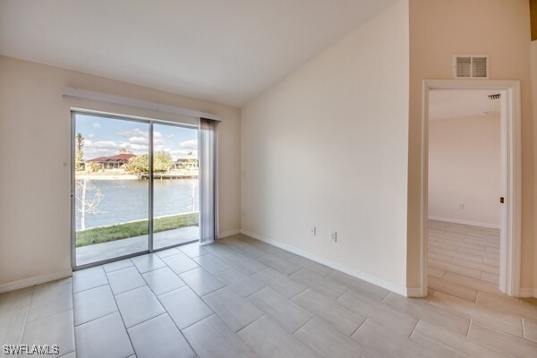 unfurnished room with a water view and lofted ceiling