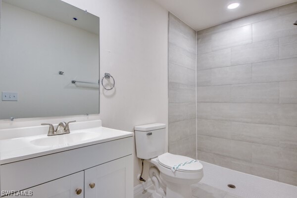 bathroom featuring a tile shower, vanity, and toilet