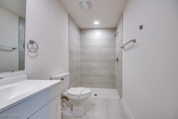 bathroom featuring tiled shower, vanity, and toilet