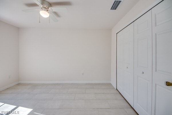 unfurnished bedroom with ceiling fan, light tile patterned flooring, and a closet