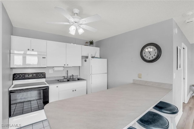 kitchen featuring white cabinets, a kitchen breakfast bar, white appliances, and sink