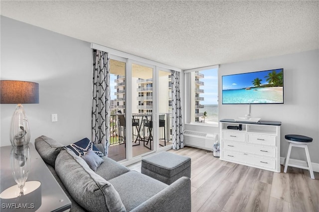 living room featuring a textured ceiling, light wood-type flooring, expansive windows, and radiator