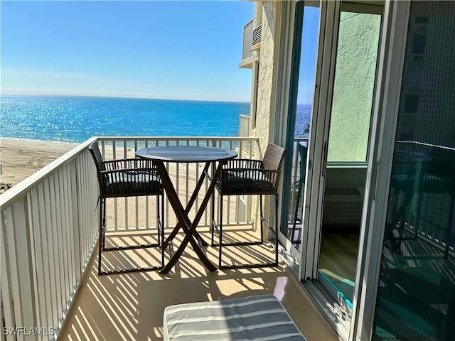 balcony with a water view and a view of the beach