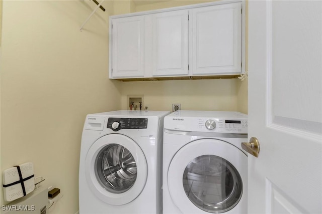 laundry room featuring washer and dryer and cabinets