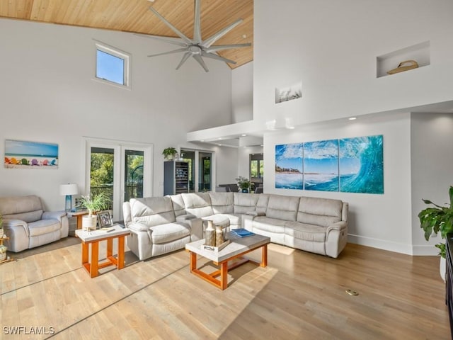 living room featuring ceiling fan, wood ceiling, a high ceiling, and light hardwood / wood-style flooring