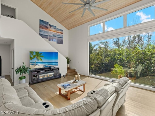 living room with a high ceiling, light hardwood / wood-style floors, ceiling fan, and wooden ceiling