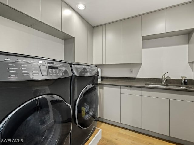 washroom featuring cabinets, light wood-type flooring, separate washer and dryer, and sink