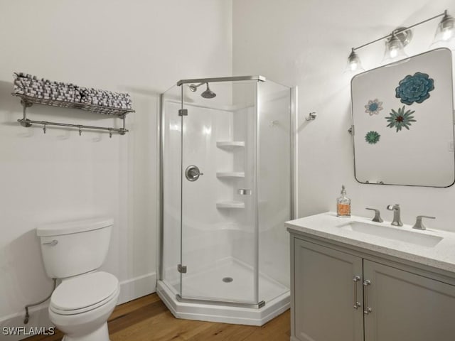 bathroom with vanity, wood-type flooring, a shower with shower door, and toilet