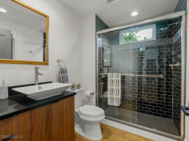 bathroom featuring hardwood / wood-style floors, vanity, a shower with shower door, and toilet