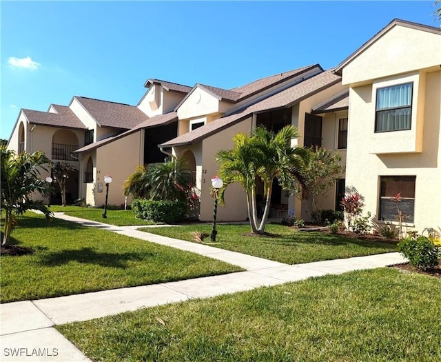 townhome / multi-family property with stucco siding and a front yard