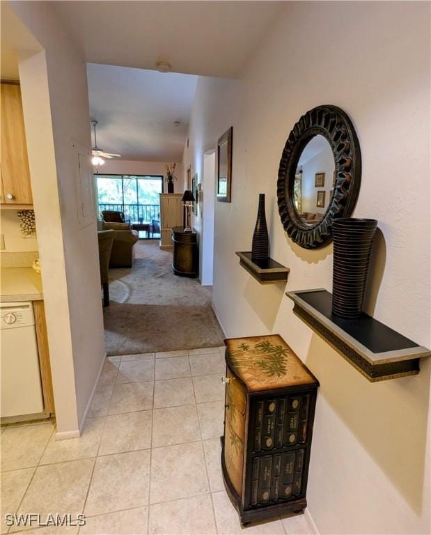 hallway featuring light carpet, baseboards, and light tile patterned flooring