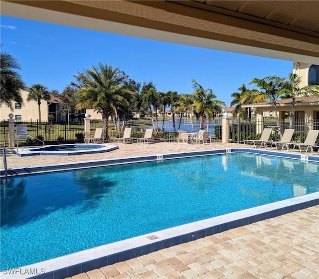 community pool with a patio area, fence, and a community hot tub