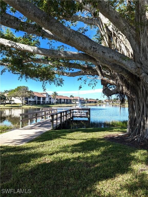 dock area with a water view, a residential view, and a lawn