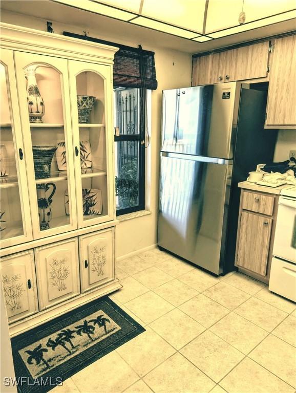 kitchen with stainless steel refrigerator, electric range, and light tile patterned flooring