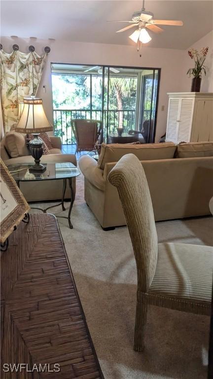 living area featuring a ceiling fan, light colored carpet, a healthy amount of sunlight, and lofted ceiling