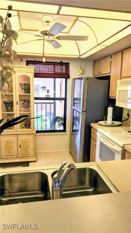 kitchen with a sink, white appliances, light countertops, and a ceiling fan