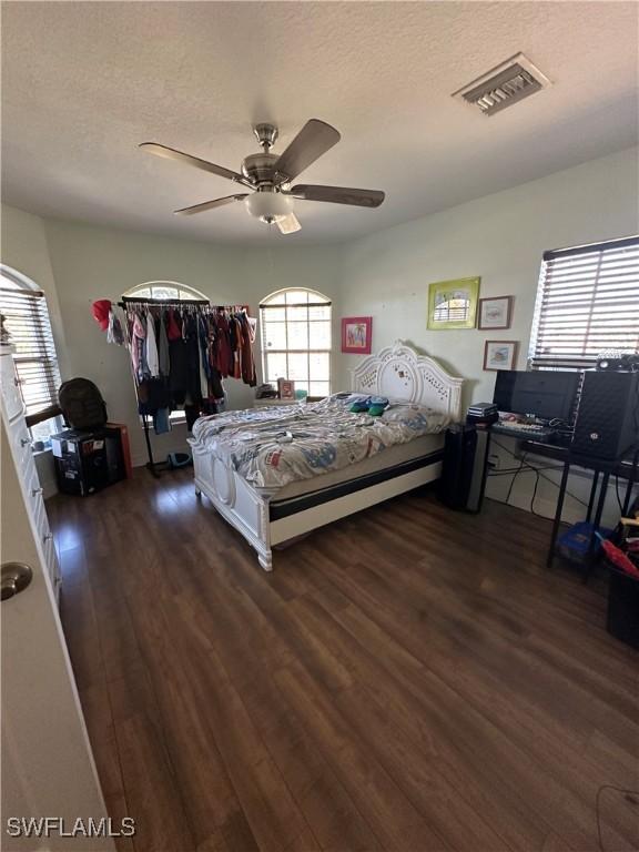 bedroom with ceiling fan, dark hardwood / wood-style flooring, and a textured ceiling