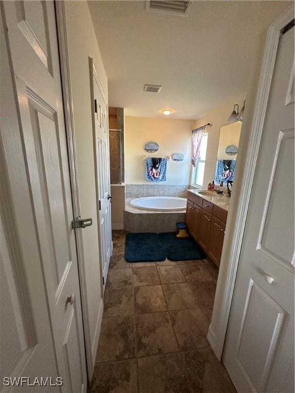 bathroom with a relaxing tiled tub and vanity