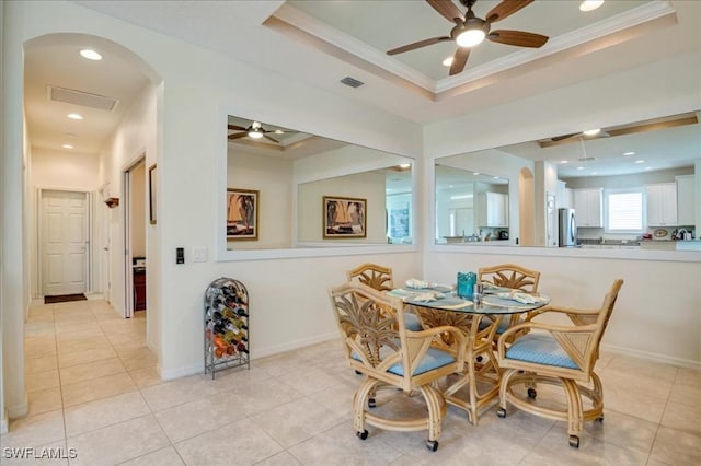 dining room with a tray ceiling, ceiling fan, ornamental molding, and light tile patterned flooring