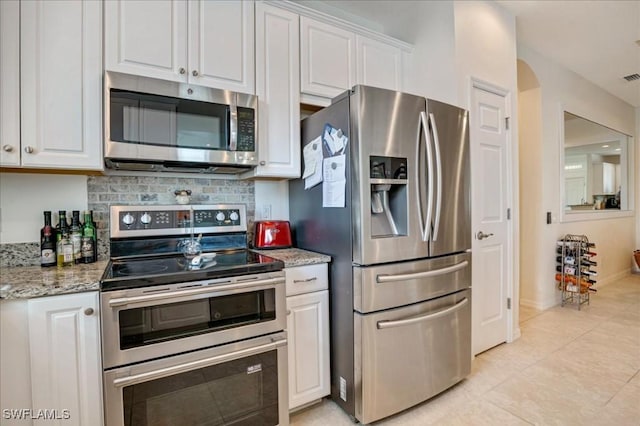 kitchen featuring white cabinets, appliances with stainless steel finishes, tasteful backsplash, and light stone counters