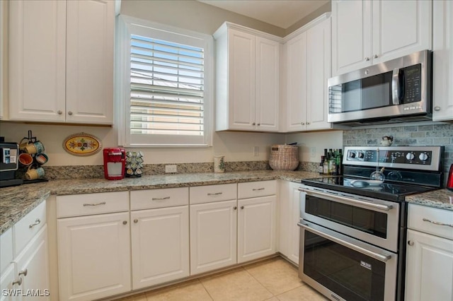 kitchen with light stone countertops, white cabinetry, light tile patterned floors, and stainless steel appliances