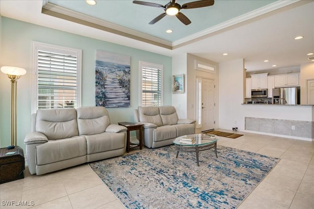 living room with light tile patterned floors, a tray ceiling, ceiling fan, and ornamental molding