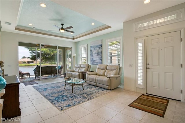 living room with light tile patterned floors, a raised ceiling, and ceiling fan