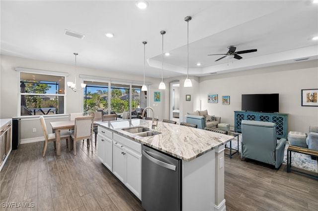 kitchen with pendant lighting, dishwasher, white cabinets, sink, and a tray ceiling