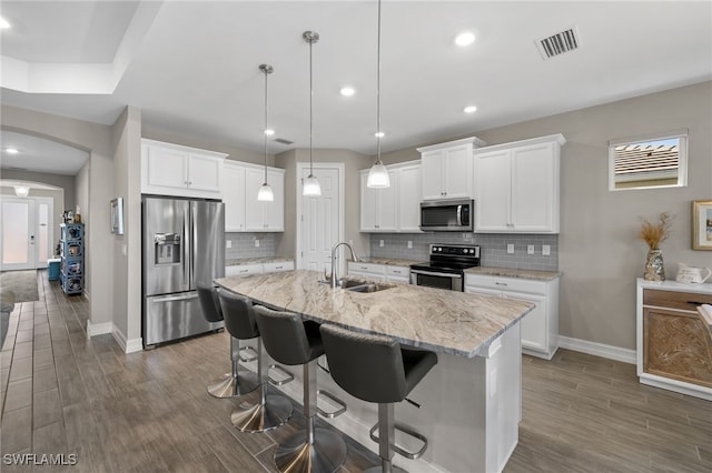 kitchen with white cabinetry, sink, stainless steel appliances, and a center island with sink