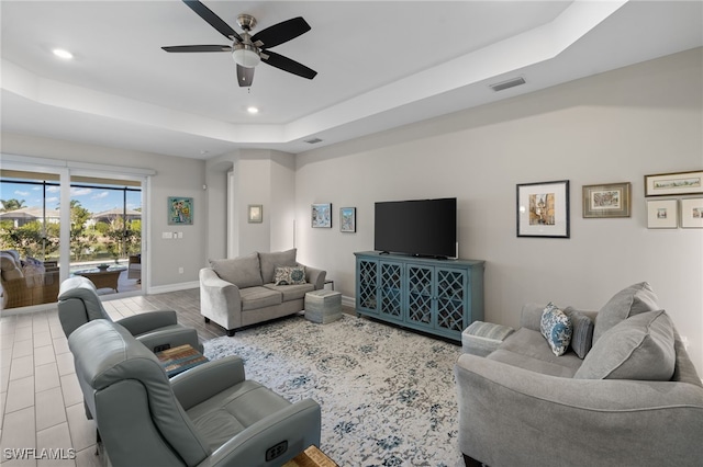 living room with a tray ceiling and ceiling fan