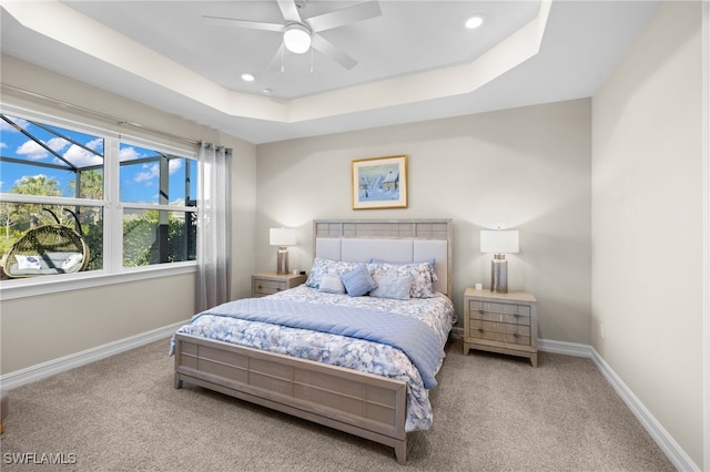 carpeted bedroom featuring a raised ceiling and ceiling fan