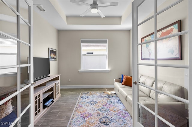 sitting room featuring french doors, a tray ceiling, and ceiling fan