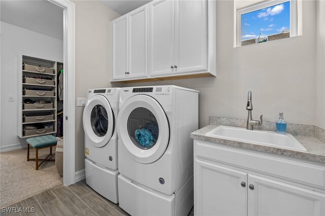 laundry room with washing machine and clothes dryer, sink, and cabinets