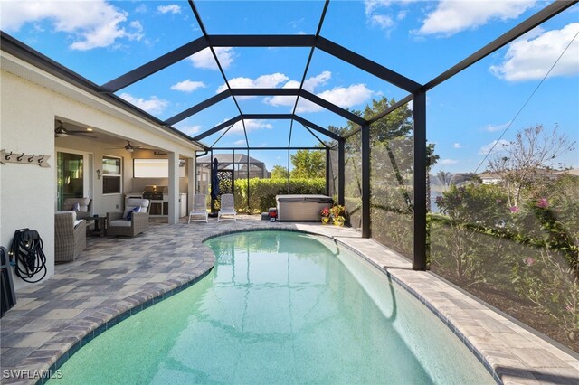 view of swimming pool with ceiling fan, exterior kitchen, a lanai, a hot tub, and a patio area