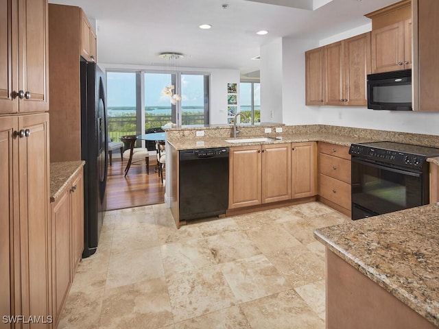 kitchen featuring light stone countertops, sink, hanging light fixtures, kitchen peninsula, and black appliances