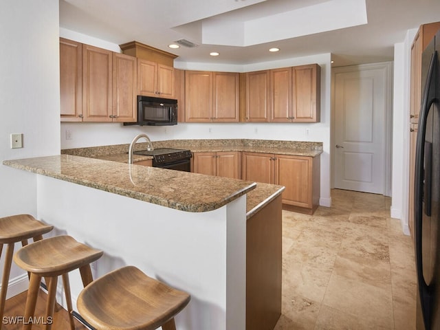 4951 Bonita Bay Blvd Unit 604, Bonita Springs, FL 34134 - kitchen featuring black appliances, a kitchen breakfast bar, a peninsula, recessed lighting, and brown cabinets