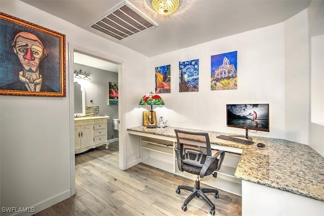 home office with built in desk and light hardwood / wood-style floors