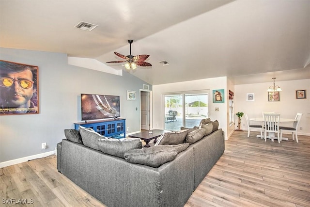 living room featuring ceiling fan with notable chandelier, wood-type flooring, and vaulted ceiling