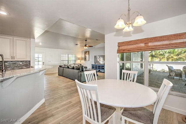 dining room with ceiling fan with notable chandelier and light wood-type flooring