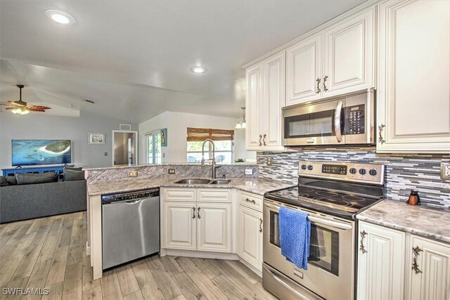 kitchen with kitchen peninsula, appliances with stainless steel finishes, sink, white cabinets, and lofted ceiling