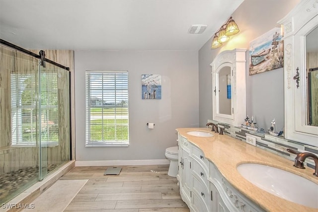 bathroom with vanity, toilet, wood-type flooring, and a shower with door