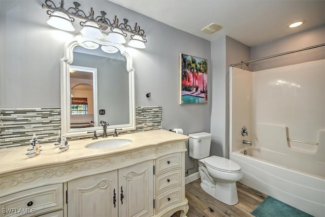 full bathroom featuring hardwood / wood-style floors, vanity, backsplash, bathtub / shower combination, and toilet