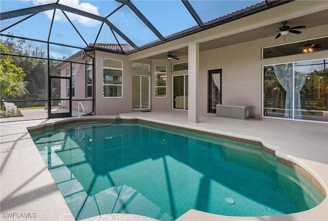 view of swimming pool with glass enclosure, ceiling fan, and a patio area